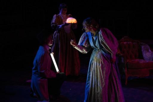 Students in old fashioned gowns under dim colorful lights